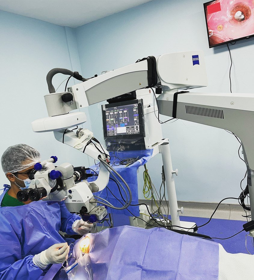 Dr. Leonardo Eloy operando ao microscópio em sala cirúrgica oftalmológica